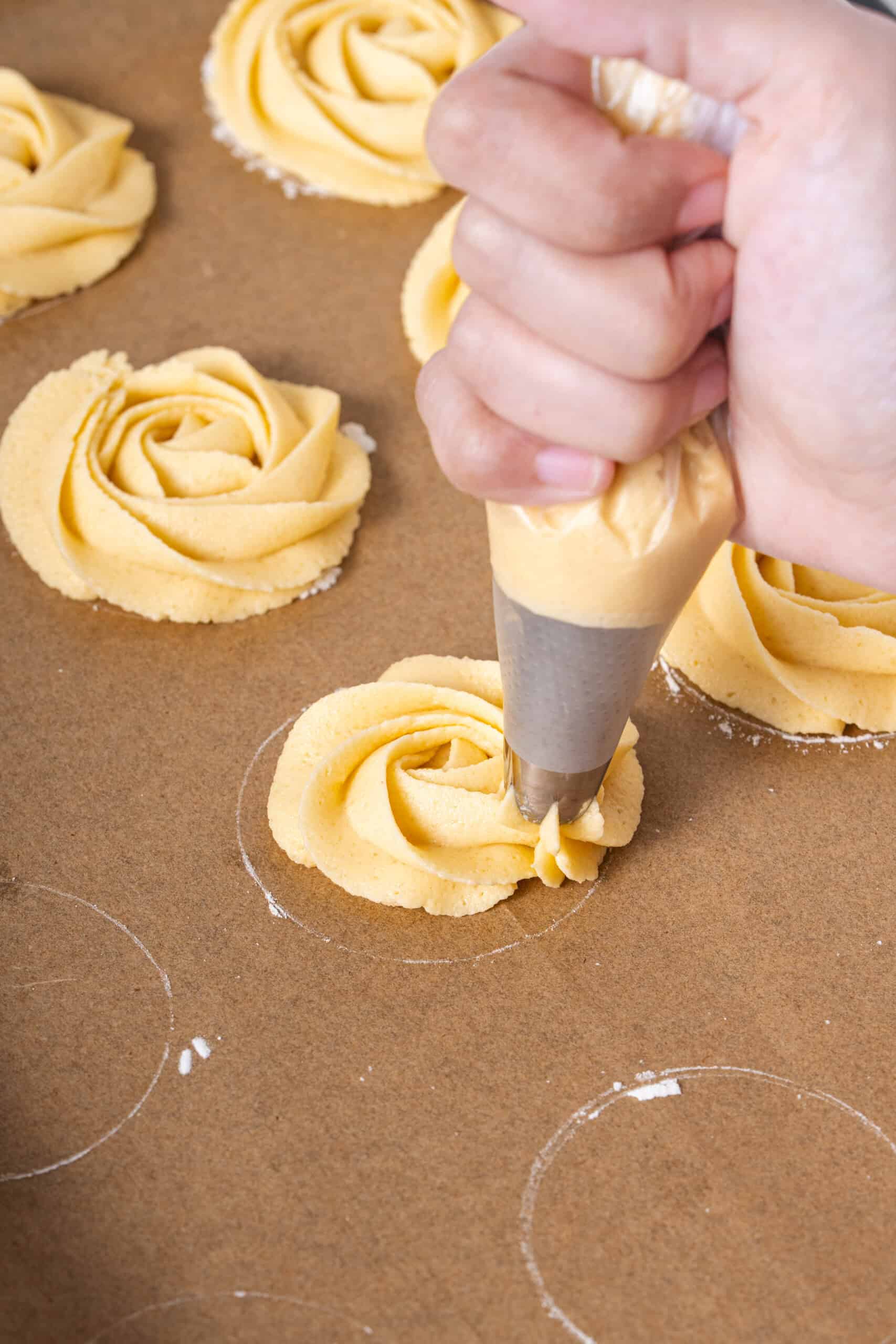cookie dough piped into rosette shapes on a baking sheet.