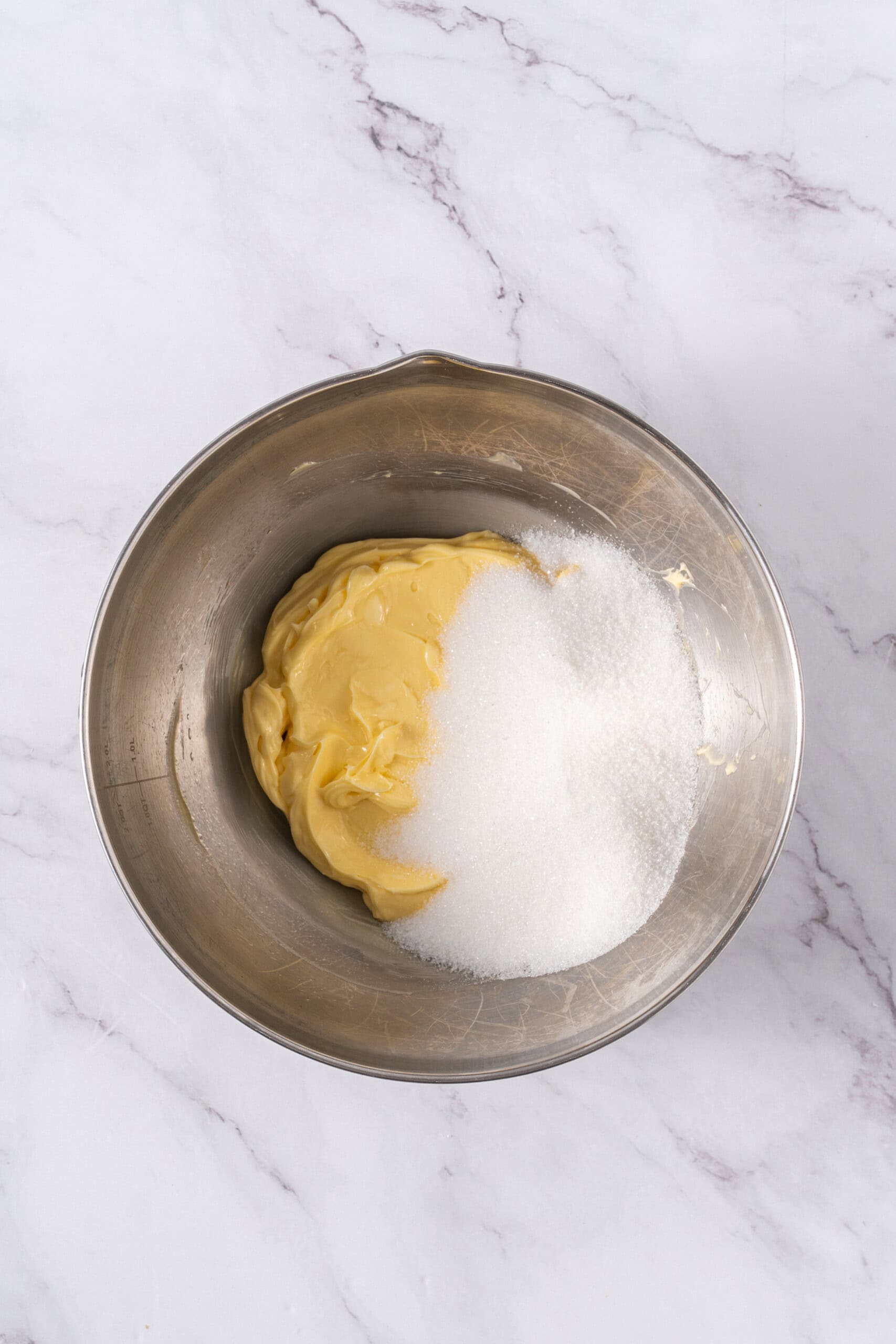 Butter and granulated sugar in a stainless steel mixing bowl.