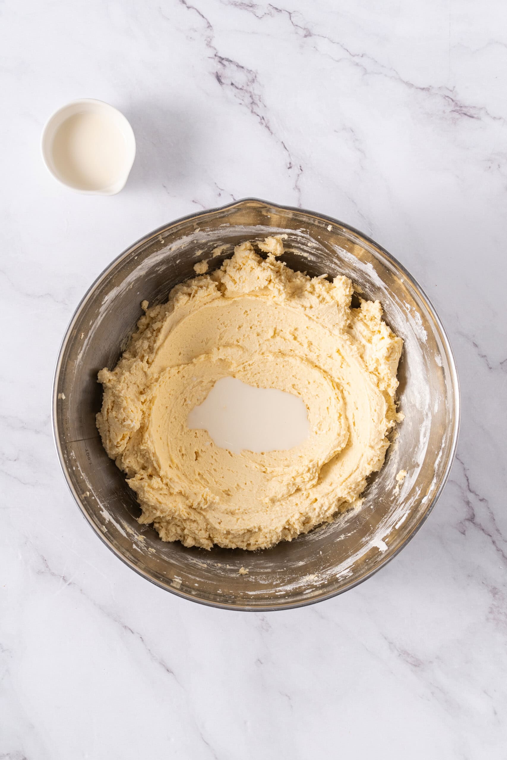 Milk added to cookie dough in a mixing bowl.