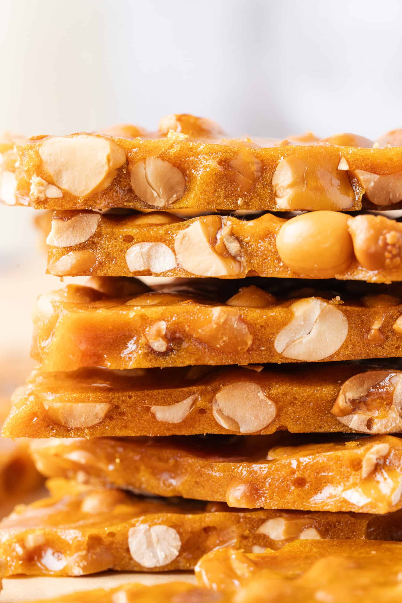 Close-up of stacked homemade peanut brittle showing thin caramel layers packed with peanuts.