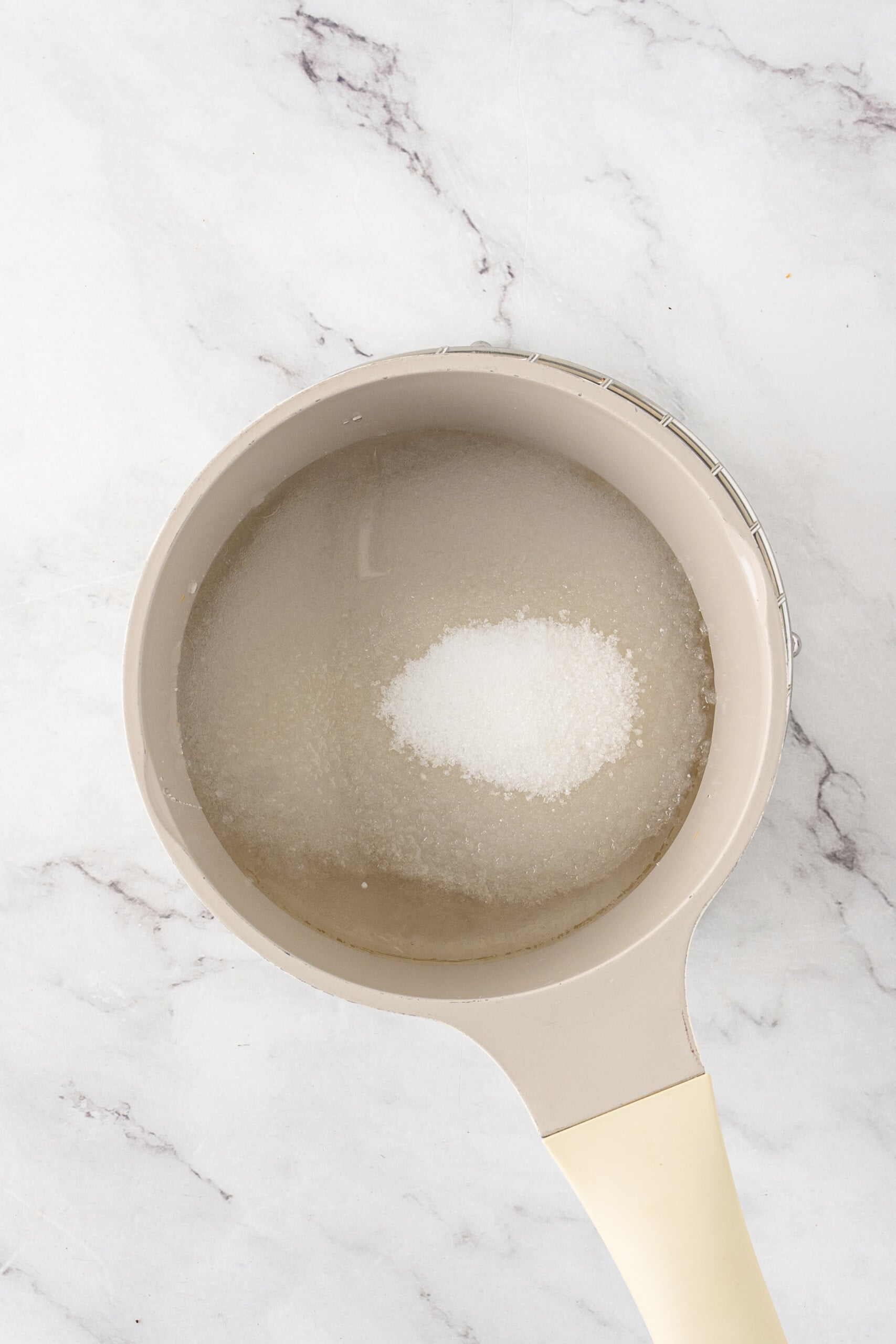 Granulated sugar added to a saucepan of water.