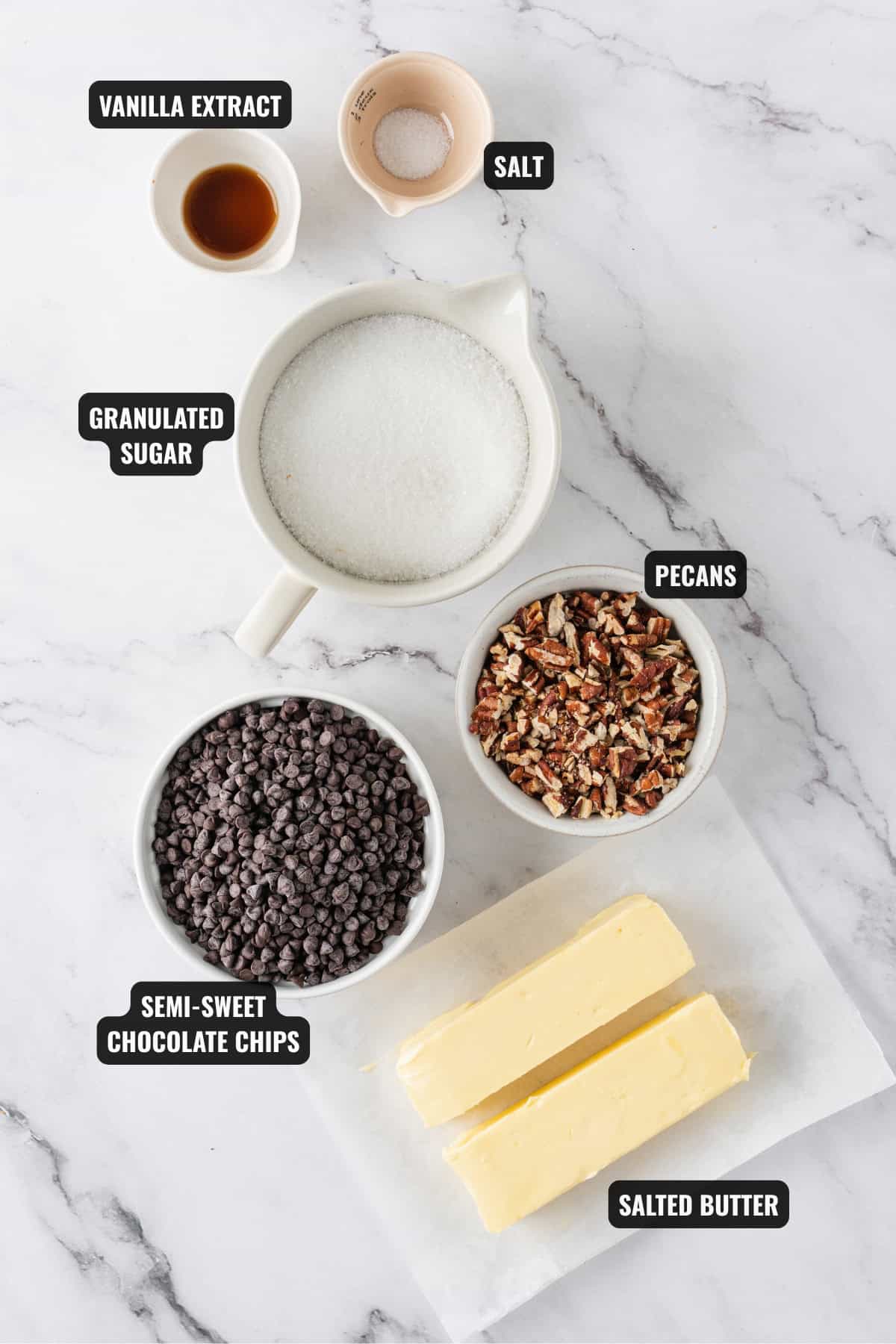 ingredients for homemade toffee recipe including granulated sugar, pecans, salted butter, chocolate chips, vanilla extract, and salt