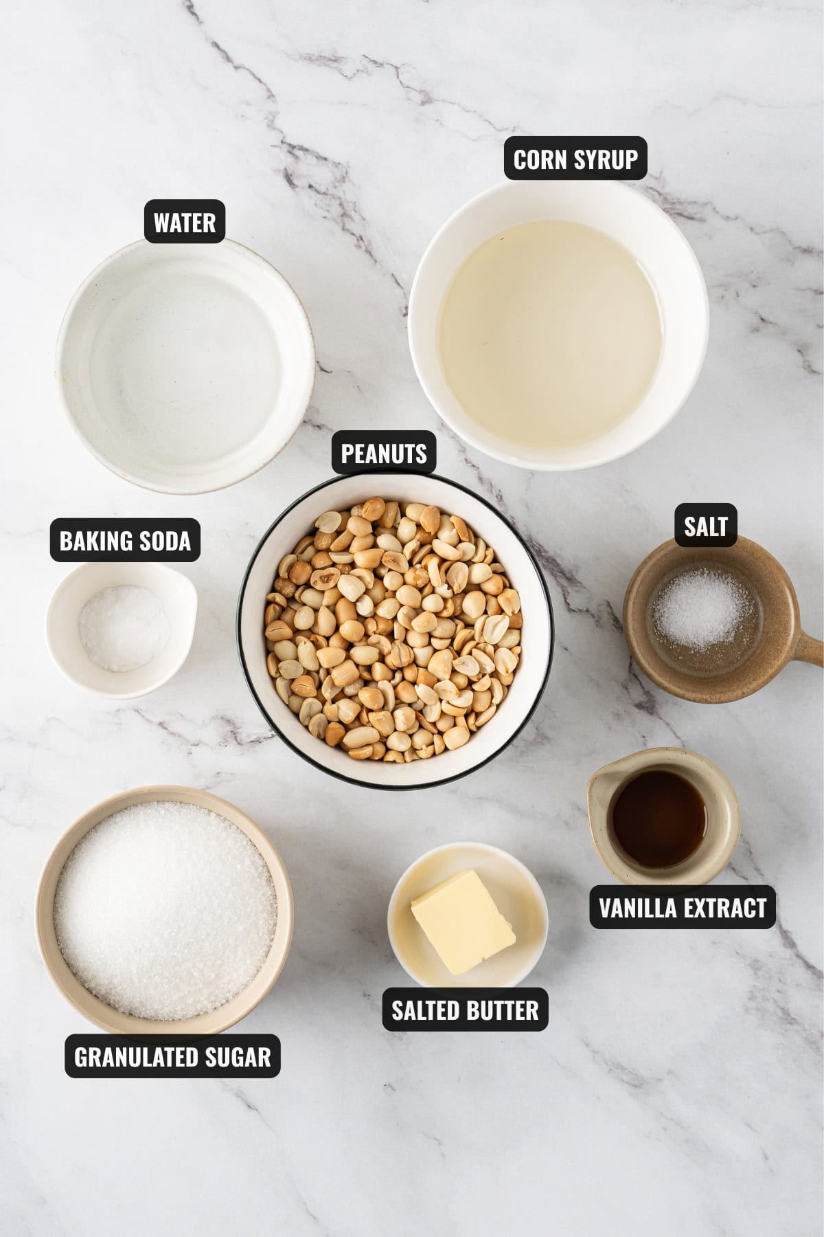 ingredients for peanut brittle recipe including peanuts, granulated sugar, salted butter, vanilla extract, salt, baking soda, water, and corn syrup